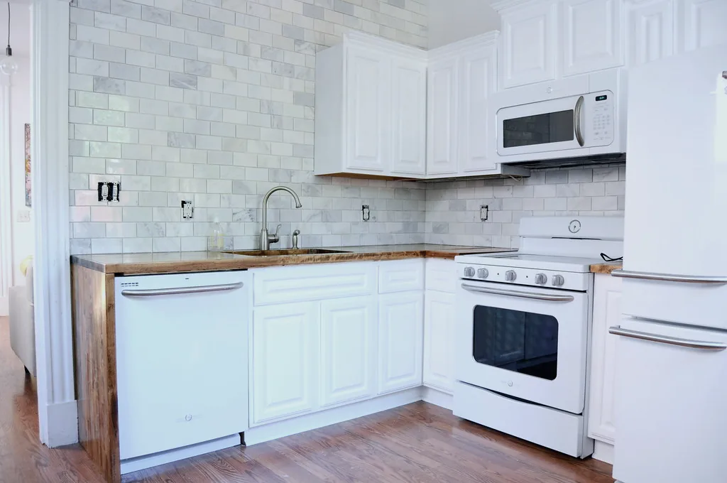 Cocina de un hogar con nevera, lavavajillas y horno; ejemplo de los electrodomésticos que atendemos a domicilio.